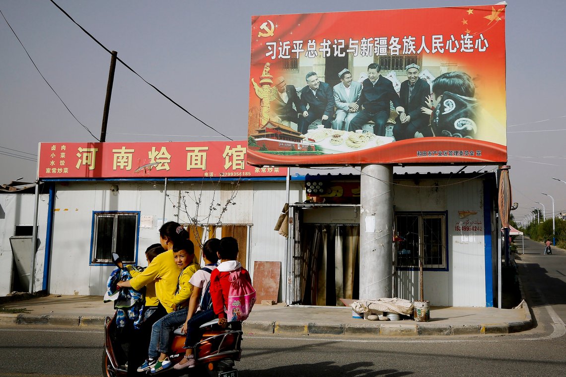 FILE - In this Sept. 20, 2018, file photo, an Uighur woman uses an electric-powered scooter to fetch school children as they ride past a picture showing China's President Xi Jinping joining hands with a group of Uighur elders at the Unity New Village in Hotan, in western China's Xinjiang region. Australia and New Zealand on Tuesday, March 23, 2021 welcomed the United States, European Union, Canada and Britain taking joint action to impose sanctions on senior Chinese officials over human rights abuses in China’s far western Xinjiang region. (AP Photo/Andy Wong, File) FILE - In this Sept. 20, 2018, file photo, an Uighur woman uses an electric-powered scooter to fetch school children as they ride past a picture showing China's President Xi Jinping joining hands with a group of Uighur elders at the Unity New Village in Hotan, in western China's Xinjiang region. Australia and New Zealand on Tuesday, March 23, 2021 welcomed the United States, European Union, Canada and Britain taking joint action to impose sanctions on senior Chinese officials over human rights abuses in China’s far western Xinjiang region. (AP Photo/Andy Wong, File)