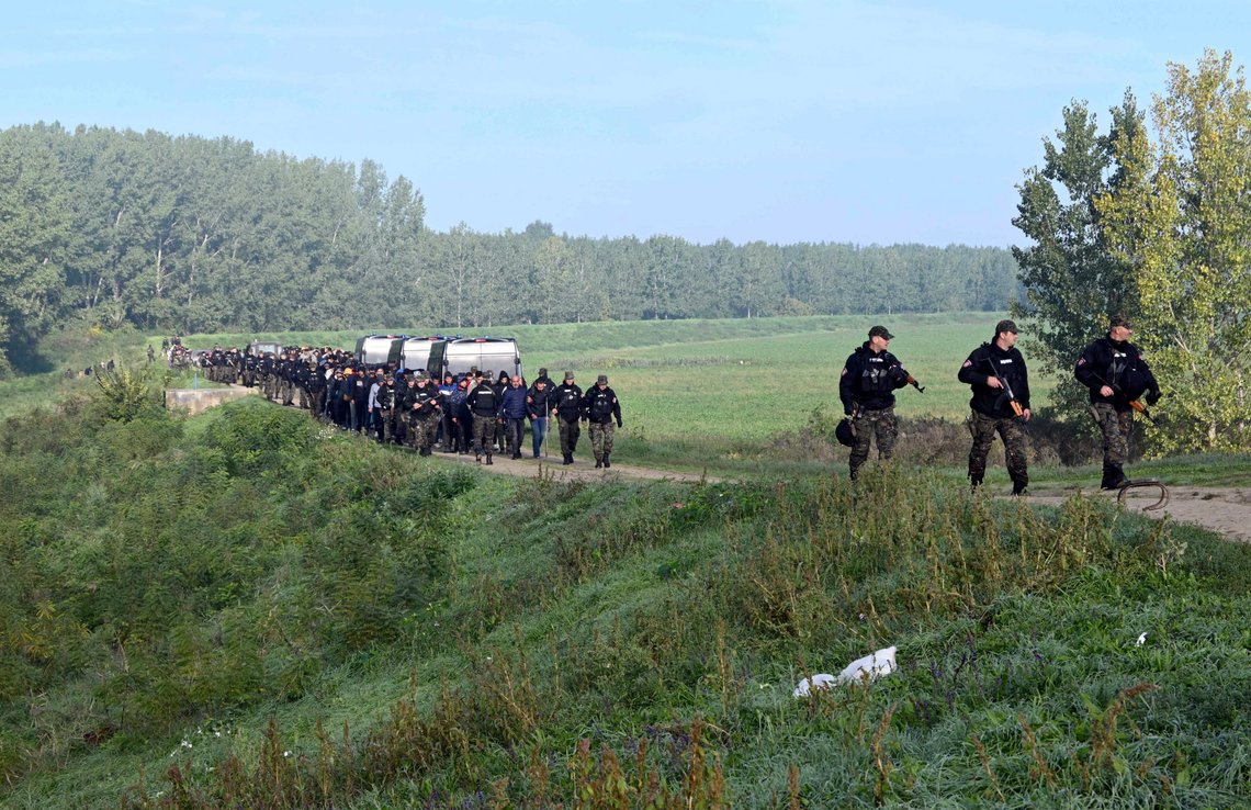 In this photo provided by the Serbian Ministry of Interior, Serbian Police officers escort migrants near village of Srpski Kustur, Serbia, Wednesday, Oct 5, 2022. Serbian police on Wednesday raided a make-shift camp near the border with Hungary where they found 200 migrants, detained people smugglers and confiscated weapons and money. (Serbian Ministry of Interior via AP) In this photo provided by the Serbian Ministry of Interior, Serbian Police officers escort migrants near village of Srpski Kustur, Serbia, Wednesday, Oct 5, 2022. Serbian police on Wednesday raided a make-shift camp near the border with Hungary where they found 200 migrants, detained people smugglers and confiscated weapons and money. (Serbian Ministry of Interior via AP)