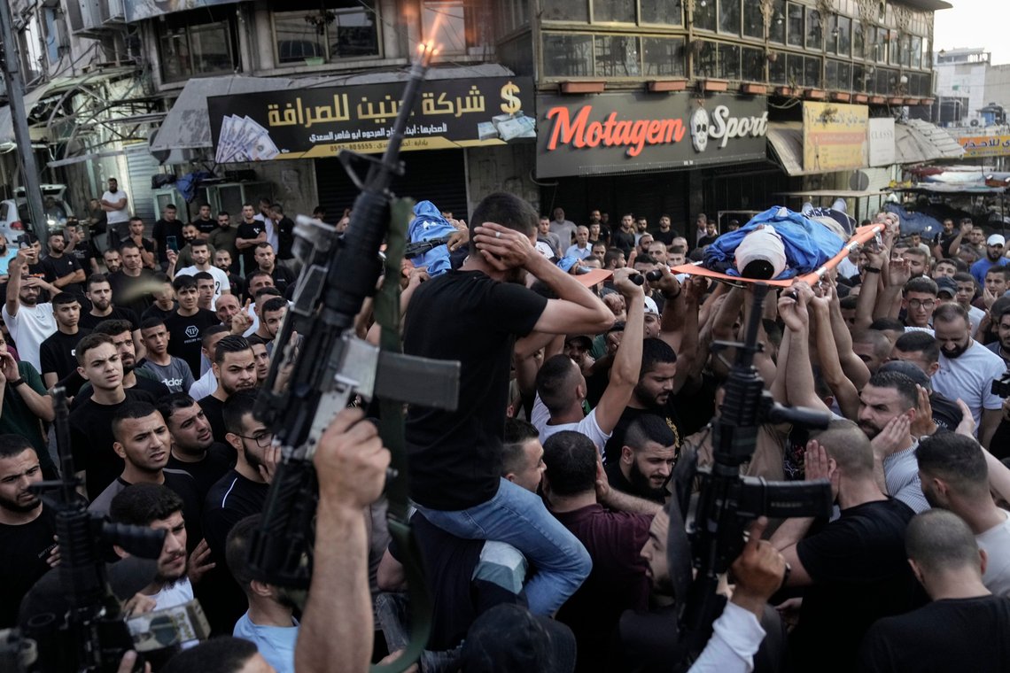A gunman fires his weapon during a march as mourners carry the bodies of Palestinians, one of them draped in the Islamic Jihad militant group flag, during their funeral in the West Bank city of Jenin, Thursday, June 6, 2024. The Palestinian Health Ministry says three Palestinians have been killed by Israeli fire in the occupied West Bank. The Israeli military said forces carrying out an arrest raid on Thursday opened fire at three individuals who had thrown explosives at them and that a helicopter struck the area. (AP Photo/Majdi Mohammed) A gunman fires his weapon during a march as mourners carry the bodies of Palestinians, one of them draped in the Islamic Jihad militant group flag, during their funeral in the West Bank city of Jenin, Thursday, June 6, 2024. The Palestinian Health Ministry says three Palestinians have been killed by Israeli fire in the occupied West Bank. The Israeli military said forces carrying out an arrest raid on Thursday opened fire at three individuals who had thrown explosives at them and that a helicopter struck the area. (AP Photo/Majdi Mohammed)