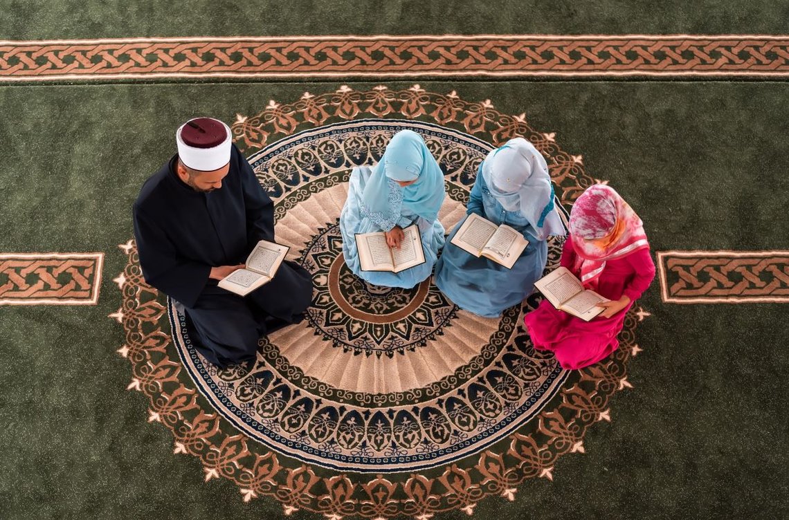 En muslimsk lærd lærer jentene å lese i den hellige boken Koranen inne i moskeen. Foto: Shutterstock av MalikNalik. En muslimsk lærd lærer jentene å lese i den hellige boken Koranen inne i moskeen. Foto: Shutterstock av MalikNalik.