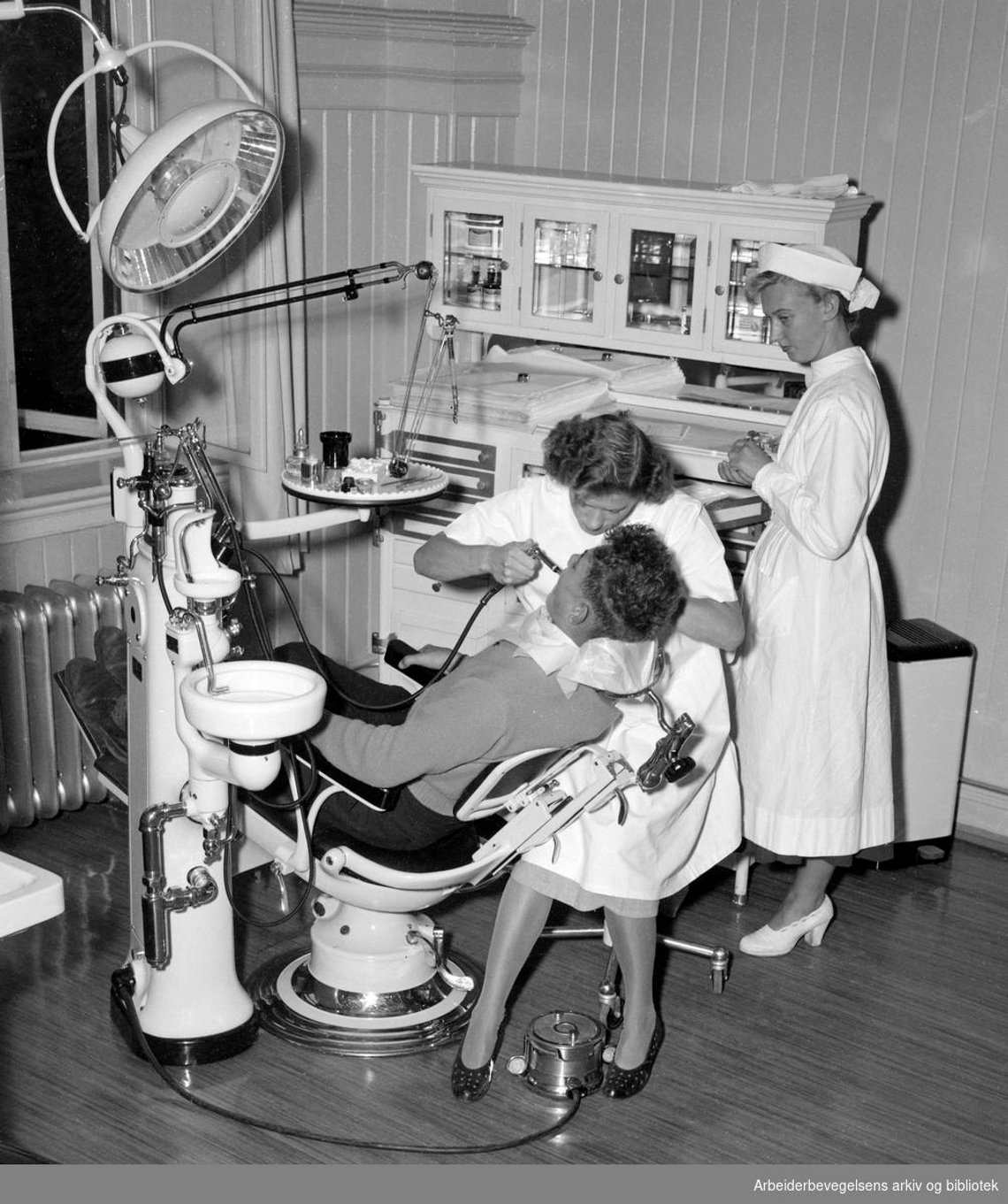 Og vi er i gang. Her i 1950. Valget av tannlege (kvinnelig) er smart. Men gjør hun vondt, eller forbereder hun aktiv barm, det er spørsmålet. (Foto: Arbeiderbladet, Arbeiderbevegelsens arkiv og bibliotek) Og vi er i gang. Her i 1950. Valget av tannlege (kvinnelig) er smart. Men gjør hun vondt, eller forbereder hun aktiv barm, det er spørsmålet. (Foto: Arbeiderbladet, Arbeiderbevegelsens arkiv og bibliotek)