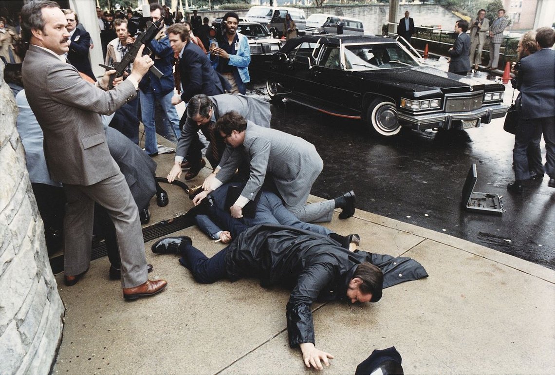 Foto av kaoset utenfor Washington Hilton Hotel etter attentatforsøket mot president Reagan. 30. Mars 1981. Kilde: Michael Evans, Det hvite hus (1981 - 1989). Wikimedia Commons. Foto av kaoset utenfor Washington Hilton Hotel etter attentatforsøket mot president Reagan. 30. Mars 1981. Kilde: Michael Evans, Det hvite hus (1981 - 1989). Wikimedia Commons.