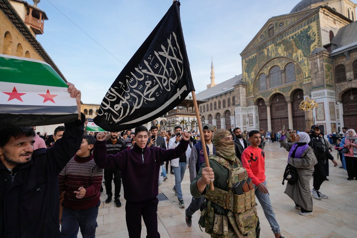 A masked opposition fighter carries a flag of Hayat Tahrir al-Sham (HTS) in the courtyard of the Umayyad Mosque in the old walled city of Damascus, Syria, on Tuesday, Dec. 10, 2024. HTS is the largest rebel faction within the opposition that toppled Bashar Assad's regime last Sunday. (AP Photo/Hussein Malla) A masked opposition fighter carries a flag of Hayat Tahrir al-Sham (HTS) in the courtyard of the Umayyad Mosque in the old walled city of Damascus, Syria, on Tuesday, Dec. 10, 2024. HTS is the largest rebel faction within the opposition that toppled Bashar Assad's regime last Sunday. (AP Photo/Hussein Malla)