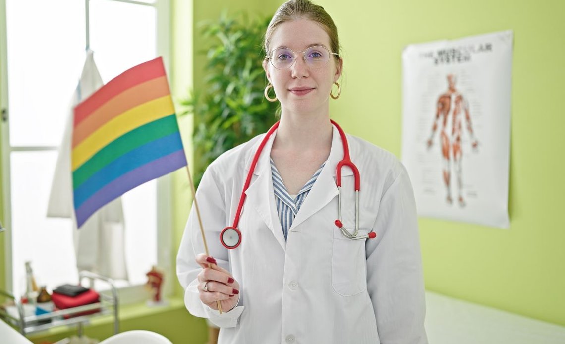 Arkivfoto av ung, blond, kvinnelig lege holder regnbueflagg på klinikk. Foto: Shutterstock av Krakenimages.com, Spania. Arkivfoto av ung, blond, kvinnelig lege holder regnbueflagg på klinikk. Foto: Shutterstock av Krakenimages.com, Spania.