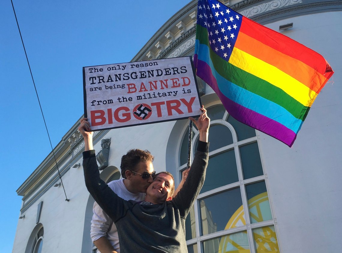 San Francisco-paret Nick Rondoletto og Doug Thorogood vifter med et regnbueflagg og holder opp en plakat for å protestere mot et foreslått forbud mot transpersoner i militæret, under en protestaksjon i 2017. Den gang havnet Donald Trumps forsøk på å stenge transpersoner ute fra militæret i rettssystemet i flere år. Nå har en dommer blokkert et nytt forsøk fra presidenten. Foto: Olga R. Rodriguez / AP / NTB San Francisco-paret Nick Rondoletto og Doug Thorogood vifter med et regnbueflagg og holder opp en plakat for å protestere mot et foreslått forbud mot transpersoner i militæret, under en protestaksjon i 2017. Den gang havnet Donald Trumps forsøk på å stenge transpersoner ute fra militæret i rettssystemet i flere år. Nå har en dommer blokkert et nytt forsøk fra presidenten. Foto: Olga R. Rodriguez / AP / NTB