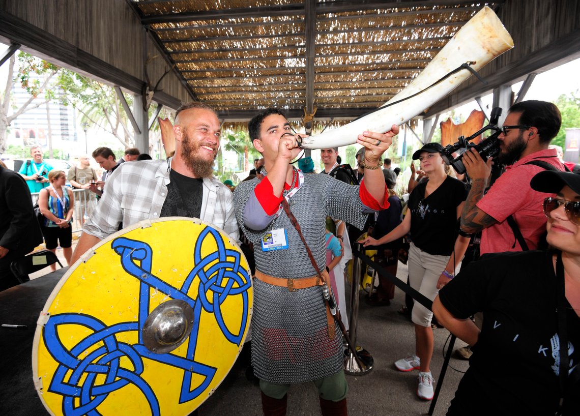 IMAGE DISTRIBUTED FOR CIVIC ENTERTAINMENT GROUP - Travis Fimmel of HISTORY's "Vikings", left, looks on as fan Michael Howell blows a horn at All Hail Vikings: An Interactive Experience outside the 2013 Comic-Con International Convention on Friday, July 19, 2013 in San Diego. Throughout the weekend, fans competed in longboat races in a custom 50-foot waterway, met with cast members and received a limited edition comic book written by series creator Michael Hirst. (Photo by Denis Poroy/Invision for HISTORY/A+E Networks/AP Images) IMAGE DISTRIBUTED FOR CIVIC ENTERTAINMENT GROUP - Travis Fimmel of HISTORY's "Vikings", left, looks on as fan Michael Howell blows a horn at All Hail Vikings: An Interactive Experience outside the 2013 Comic-Con International Convention on Friday, July 19, 2013 in San Diego. Throughout the weekend, fans competed in longboat races in a custom 50-foot waterway, met with cast members and received a limited edition comic book written by series creator Michael Hirst. (Photo by Denis Poroy/Invision for HISTORY/A+E Networks/AP Images)