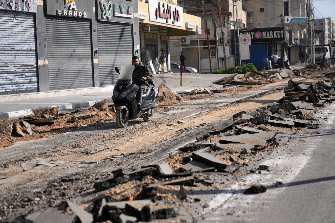 A motorcyclist rides on a street torn up in a Israeli military operation in the West Bank city of Jenin, Wednesday, Feb. 21, 2024. The Israeli army said three people were killed in an Israeli military operation in the Israeli-occupied West Bank city. Israeli troops were searching for explosives and roadside bombs during the operation, which took place overnight on Tuesday, the military said. (AP Photo/Majdi Mohammed) A motorcyclist rides on a street torn up in a Israeli military operation in the West Bank city of Jenin, Wednesday, Feb. 21, 2024. The Israeli army said three people were killed in an Israeli military operation in the Israeli-occupied West Bank city. Israeli troops were searching for explosives and roadside bombs during the operation, which took place overnight on Tuesday, the military said. (AP Photo/Majdi Mohammed)
