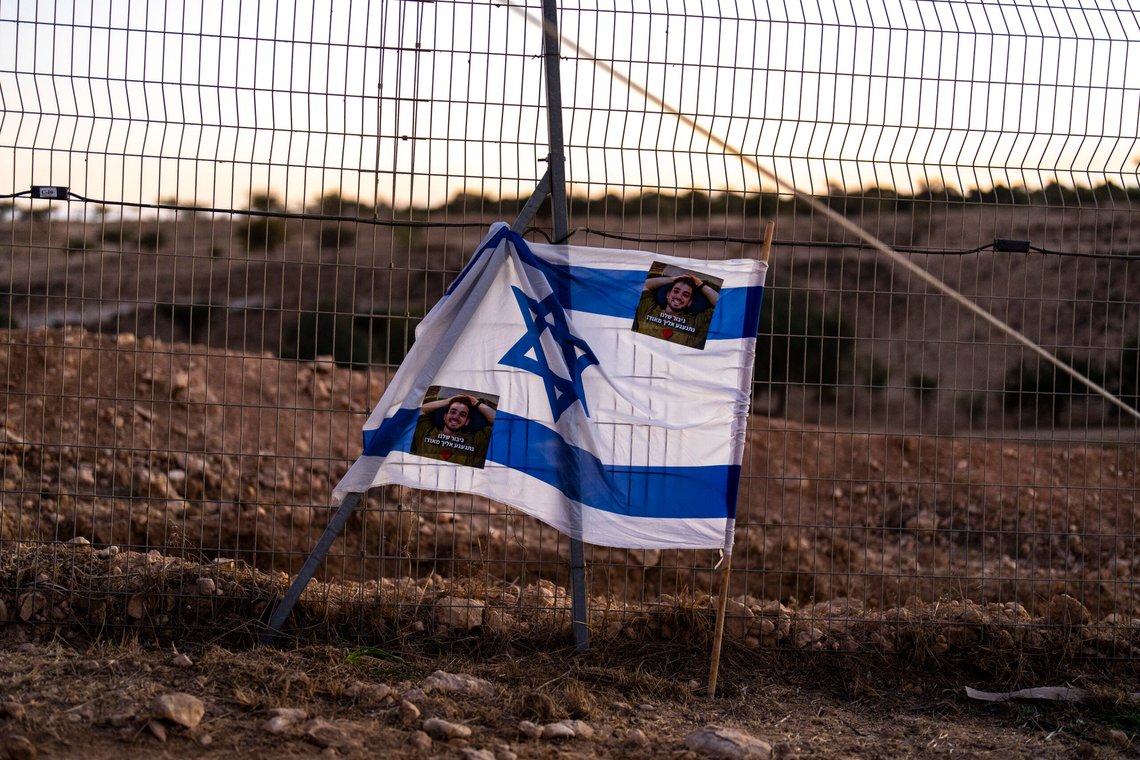 Et israelsk flagg med bilder av kaptein Yogev Pazi, som ble drept i Gaza, hang på et gjerde under hans begravelse på kirkegården i Giv'ot Bar, Sør-Israel, mandag 18. november 2024. Foto: AP /Francisco Seco/NTB Et israelsk flagg med bilder av kaptein Yogev Pazi, som ble drept i Gaza, hang på et gjerde under hans begravelse på kirkegården i Giv'ot Bar, Sør-Israel, mandag 18. november 2024. Foto: AP /Francisco Seco/NTB