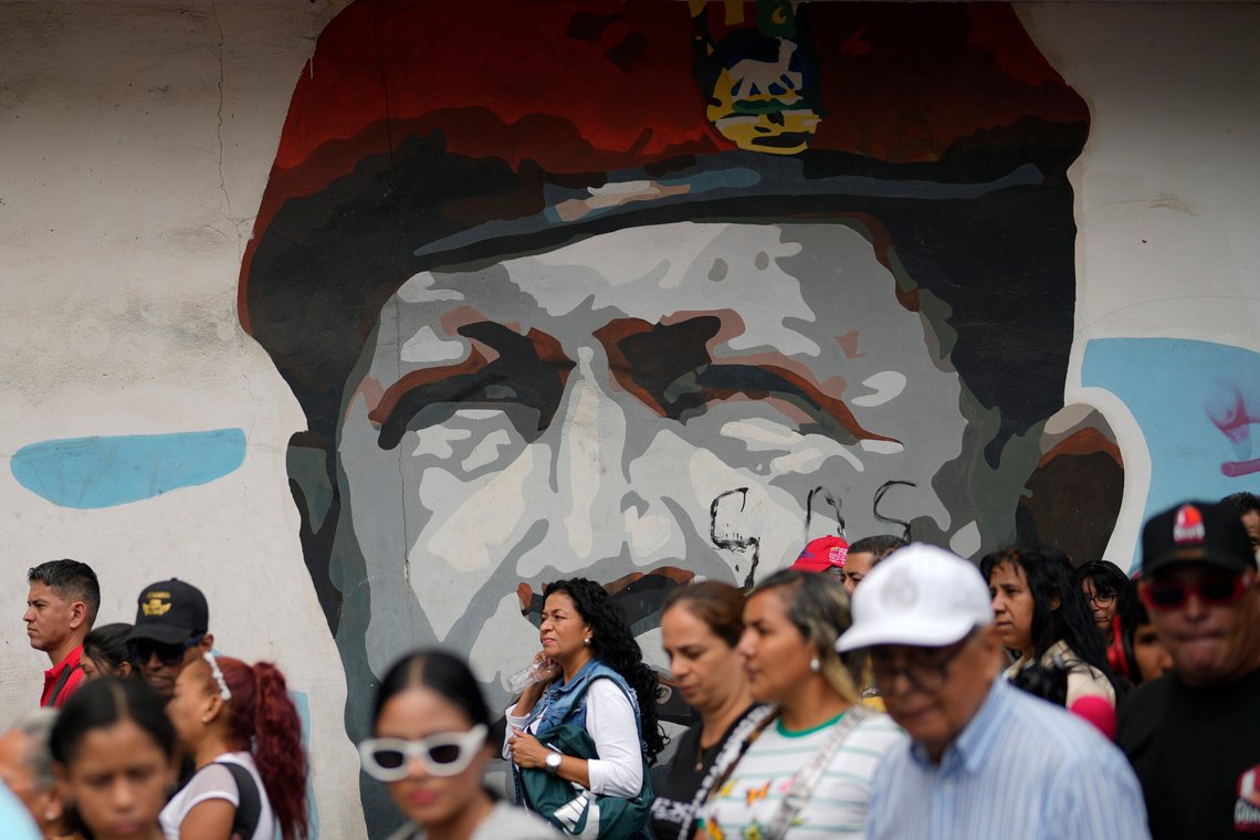 People march past a mural of late President Hugo Chavez in Caracas, Venezuela, Tuesday, March 18, 2025, during a government-organized rally to protest the deportation from the U.S. of alleged members of the Venezuelan Tren de Aragua gang, who were transferred to a prison in El Salvador. (AP Photo/Ariana Cubillos) People march past a mural of late President Hugo Chavez in Caracas, Venezuela, Tuesday, March 18, 2025, during a government-organized rally to protest the deportation from the U.S. of alleged members of the Venezuelan Tren de Aragua gang, who were transferred to a prison in El Salvador. (AP Photo/Ariana Cubillos)