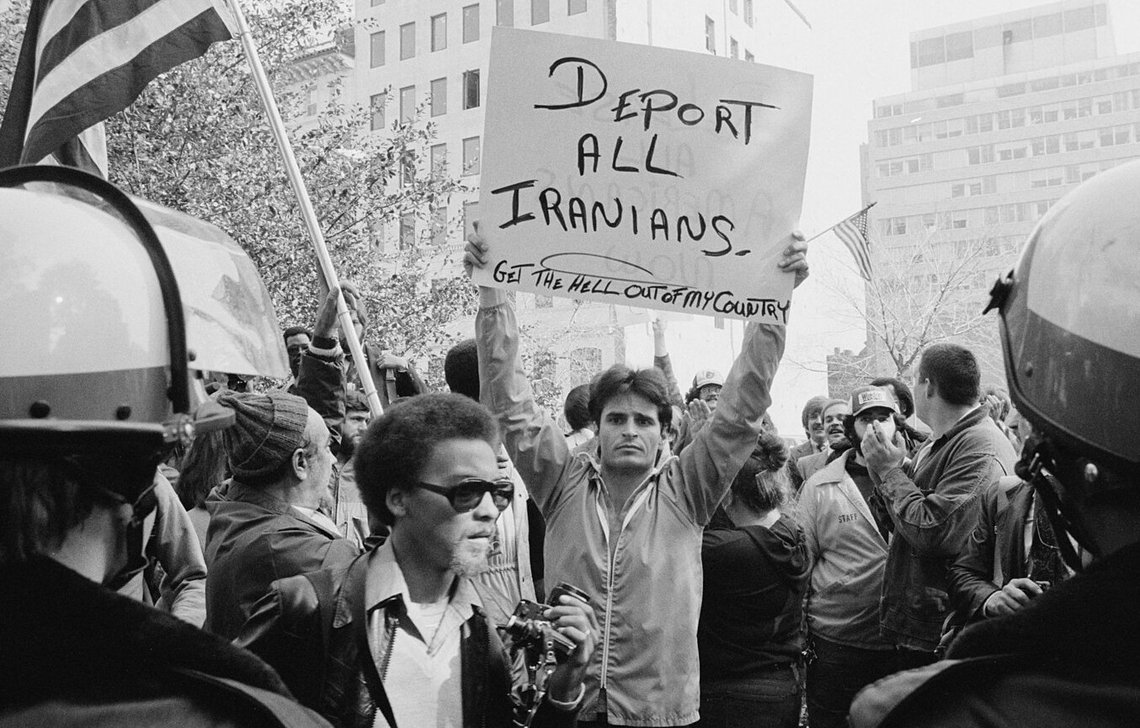 En anti-iransk demonstrasjon i Washington, D.C., i 1979. På forsiden av plakaten står det «Deport all Iranians and Get the hell out of my country» (Deporter alle iranere og kom dere ut av landet mitt), og på baksiden står det «Release all Americans now» (Løslat alle amerikanere nå). Foto: Wikepedia. En anti-iransk demonstrasjon i Washington, D.C., i 1979. På forsiden av plakaten står det «Deport all Iranians and Get the hell out of my country» (Deporter alle iranere og kom dere ut av landet mitt), og på baksiden står det «Release all Americans now» (Løslat alle amerikanere nå). Foto: Wikepedia.