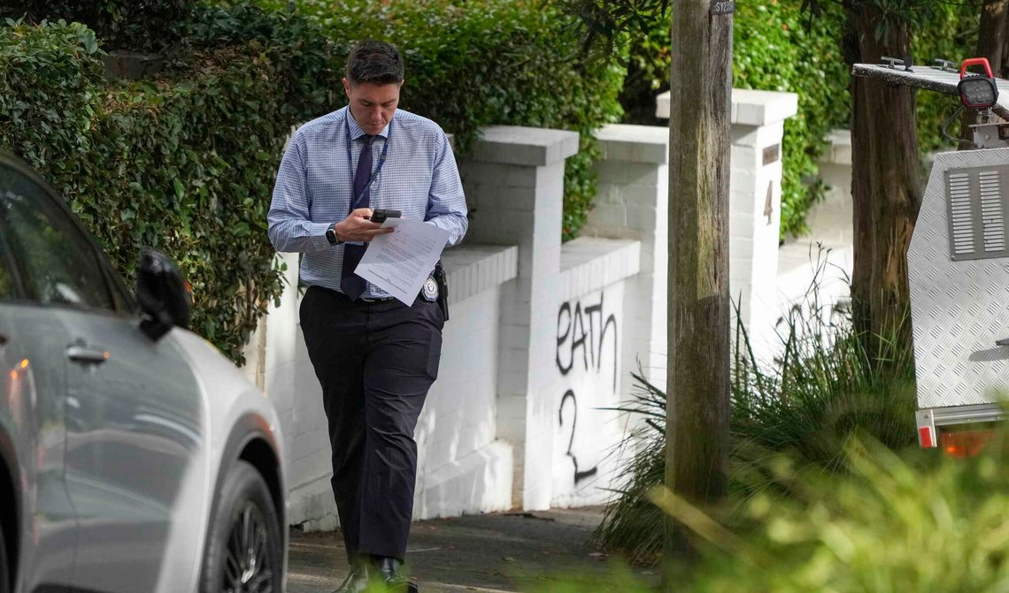 En politietterforsker går forbi hus som er vandalisert med anti-israelske slagord i Woollahra en forstaden til Sydney, den 11. desember 2024. Foto: Mark Baker / AP / NTB. En politietterforsker går forbi hus som er vandalisert med anti-israelske slagord i Woollahra en forstaden til Sydney, den 11. desember 2024. Foto: Mark Baker / AP / NTB.