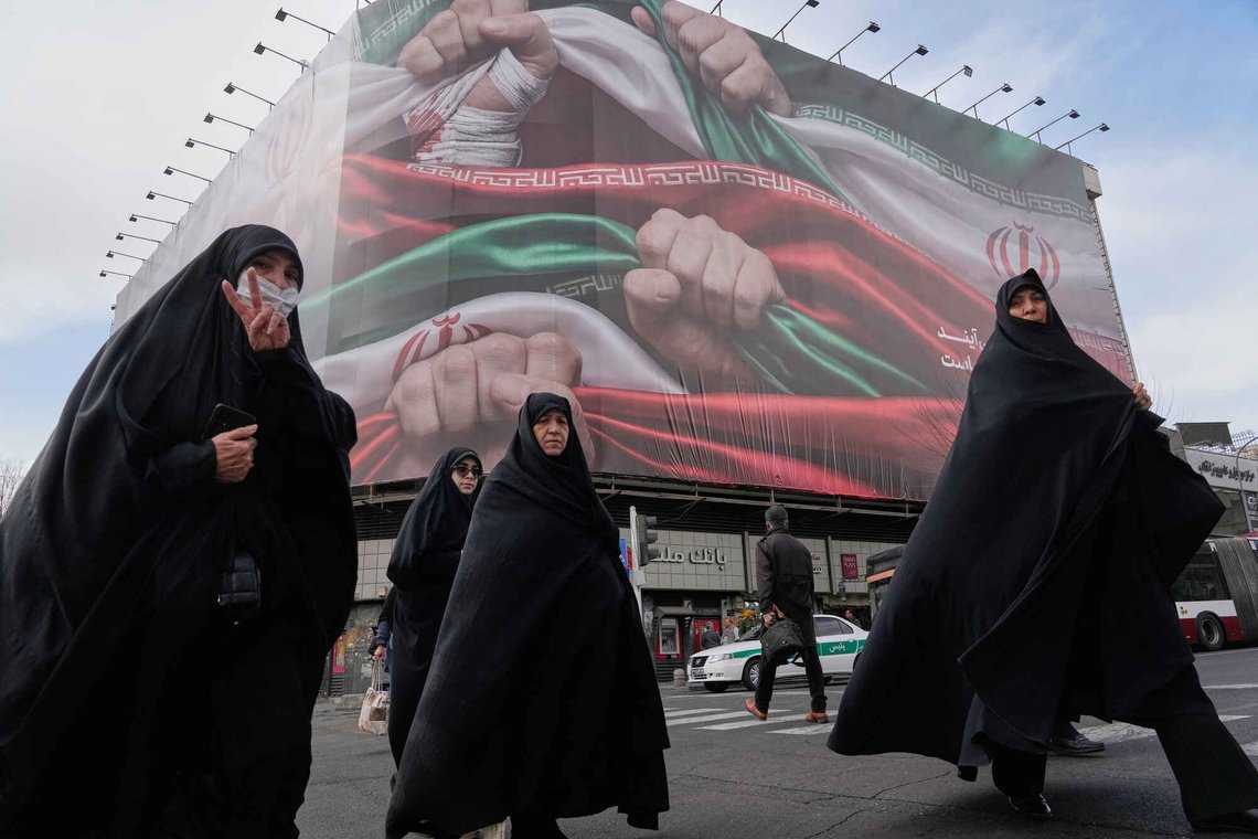 FILE - Women cross a street under a huge banner showing hands firmly holding Iranian flags as a sign of patriotism in Tehran, Iran, Jan. 14, 2026. (AP Photo/Vahid Salemi, File) FILE - Women cross a street under a huge banner showing hands firmly holding Iranian flags as a sign of patriotism in Tehran, Iran, Jan. 14, 2026. (AP Photo/Vahid Salemi, File)