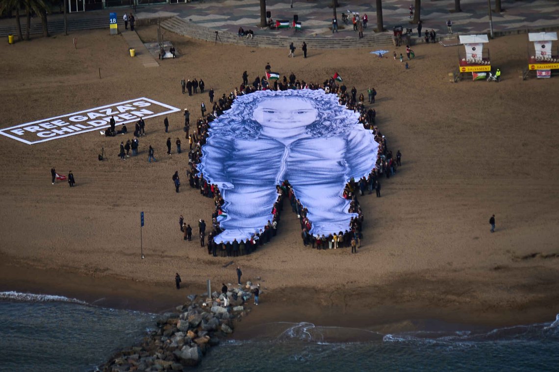 People hold a giant portrait of Hind Rajab, a five-year-old Palestinian girl who was killed during the war in Gaza, on a beach in Barcelona, Spain, Thursday, Jan. 29, 2026. (AP Photo/Emilio Morenatti) People hold a giant portrait of Hind Rajab, a five-year-old Palestinian girl who was killed during the war in Gaza, on a beach in Barcelona, Spain, Thursday, Jan. 29, 2026. (AP Photo/Emilio Morenatti)
