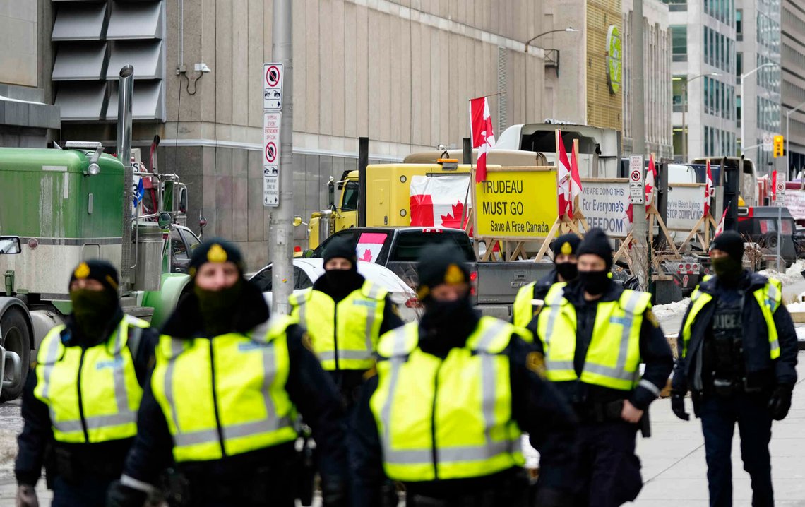 Politiet går langs Albert Street foran lastebiler som protesterer mot statsminister Justin Trudeau og den føderale liberale regjeringens covid-19-restriksjoner, 11. februar 2022, i Ottawa. Foto: Justin Tang, AP-NTB. Politiet går langs Albert Street foran lastebiler som protesterer mot statsminister Justin Trudeau og den føderale liberale regjeringens covid-19-restriksjoner, 11. februar 2022, i Ottawa. Foto: Justin Tang, AP-NTB.