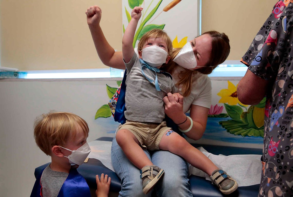 «Gi publikum en applaus!», roper Jen Maddock mens hun løfter knyttneven i jubel sammen med sønnen Will, 23 måneder, etter at gutten fikk sin covid-19-vaksine hos Southwest Pediatrics den 22. juni 2022 i St. Louis. Will og broren Jack, 3, som venter på sin tur til venstre, hadde på seg superheltkapper for anledningen. Foto: Robert Cohen, AP-NTB. «Gi publikum en applaus!», roper Jen Maddock mens hun løfter knyttneven i jubel sammen med sønnen Will, 23 måneder, etter at gutten fikk sin covid-19-vaksine hos Southwest Pediatrics den 22. juni 2022 i St. Louis. Will og broren Jack, 3, som venter på sin tur til venstre, hadde på seg superheltkapper for anledningen. Foto: Robert Cohen, AP-NTB.