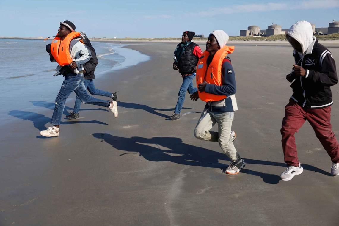 Migranter i Gravelines i Nord-Frankrike løper for å komme seg om bord i en båt i et forsøk på å nå Storbritannia den 19. september 2025. Foto: Jean-Francois Badias / AP / NTB. Migranter i Gravelines i Nord-Frankrike løper for å komme seg om bord i en båt i et forsøk på å nå Storbritannia den 19. september 2025. Foto: Jean-Francois Badias / AP / NTB.
