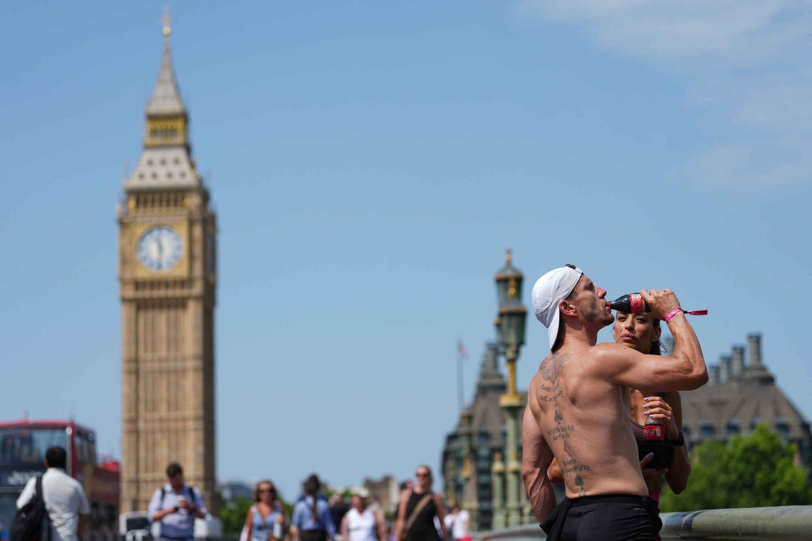 En ung mann drikker brus på Westminster Bridge i London. Britene gjør hva de kan for å takle hetebølgen, men mange nektes å ta i bruk klimaanlegg av hensyn til målet om Net Zero. Foto: AP /Kirsty Wigglesworth/ NTB En ung mann drikker brus på Westminster Bridge i London. Britene gjør hva de kan for å takle hetebølgen, men mange nektes å ta i bruk klimaanlegg av hensyn til målet om Net Zero. Foto: AP /Kirsty Wigglesworth/ NTB