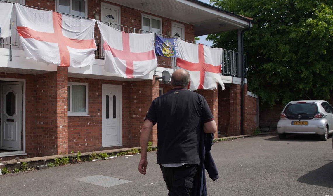 En mann går forbi boliger i Makerfield i England som er dekorert med engelske St. George-flagg den 22. mai 2026. Foto: Ian Hodgson / AP / NTB. En mann går forbi boliger i Makerfield i England som er dekorert med engelske St. George-flagg den 22. mai 2026. Foto: Ian Hodgson / AP / NTB.