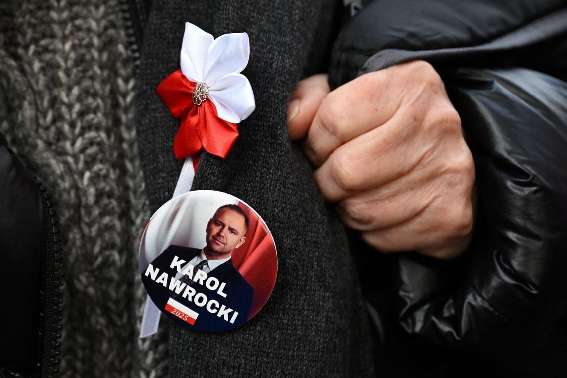 A pin depicting Poland's President Karol Nawrocki is seen on a protester's jacket during a rally outside the headquarters of Poland's Constitutional Court in Warsaw on October 31, 2026, after police blocked access to the building. Poland's President Karol Nawrocki called off a visit to Africa in mid-flight as riot police deployed around the country's constitutional court on October 30 following the suspension of its chief justice in a battle between the centrist government and the nationalist right. Dozens of police guarded the entrance to the court as followers of the opposition right-wing Law and Justice party (PiS) protested the ousting of constitutional court president Bogdan Swieczkowski. (Photo by Sergei GAPON / AFP) A pin depicting Poland's President Karol Nawrocki is seen on a protester's jacket during a rally outside the headquarters of Poland's Constitutional Court in Warsaw on October 31, 2026, after police blocked access to the building. Poland's President Karol Nawrocki called off a visit to Africa in mid-flight as riot police deployed around the country's constitutional court on October 30 following the suspension of its chief justice in a battle between the centrist government and the nationalist right. Dozens of police guarded the entrance to the court as followers of the opposition right-wing Law and Justice party (PiS) protested the ousting of constitutional court president Bogdan Swieczkowski. (Photo by Sergei GAPON / AFP)