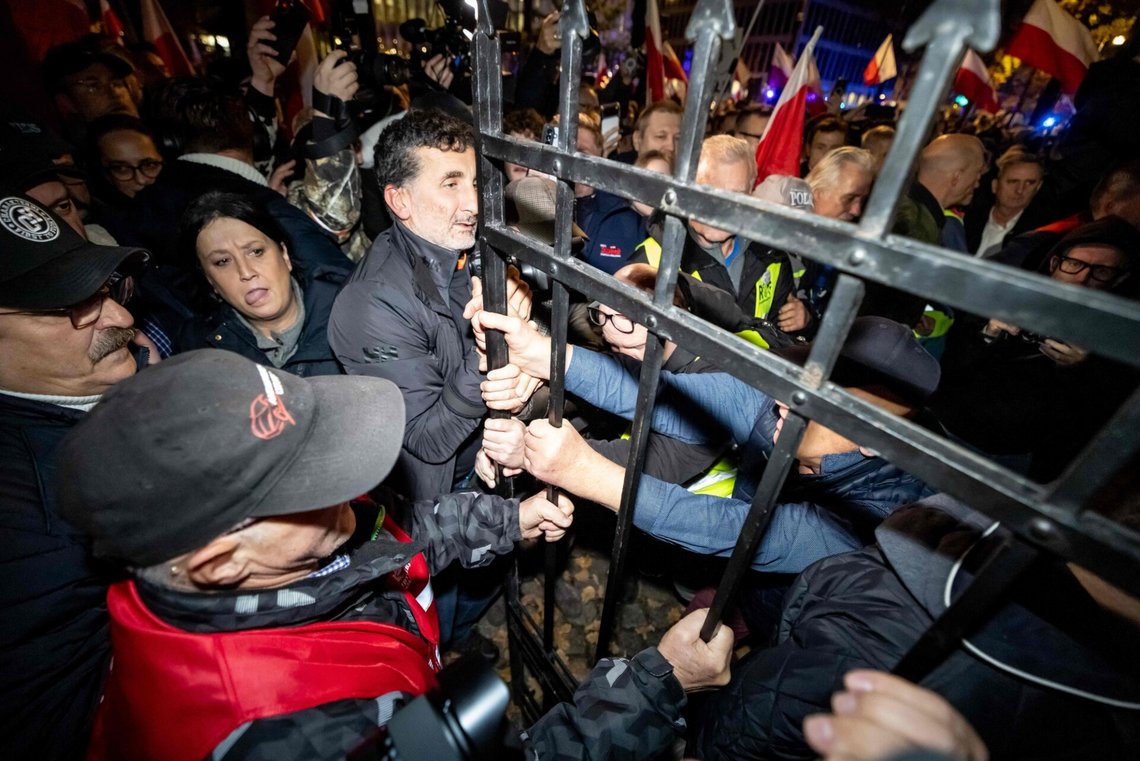 Protesters force open a metal gate leading to the courtyard outside the headquarters of Poland's Constitutional Court after police blocked access to the building in Warsaw, Poland on October 30, 2026. Poland's President Karol Nawrocki called off a visit to Africa in mid-flight as riot police deployed around the country's constitutional court on October 30 following the suspension of its chief justice in a battle between the centrist government and the nationalist right. Dozens of police guarded the entrance to the court as followers of the opposition right-wing Law and Justice party (PiS) protested the ousting of constitutional court president Bogdan Swieczkowski. (Photo by Wojtek RADWANSKI / AFP) Protesters force open a metal gate leading to the courtyard outside the headquarters of Poland's Constitutional Court after police blocked access to the building in Warsaw, Poland on October 30, 2026. Poland's President Karol Nawrocki called off a visit to Africa in mid-flight as riot police deployed around the country's constitutional court on October 30 following the suspension of its chief justice in a battle between the centrist government and the nationalist right. Dozens of police guarded the entrance to the court as followers of the opposition right-wing Law and Justice party (PiS) protested the ousting of constitutional court president Bogdan Swieczkowski. (Photo by Wojtek RADWANSKI / AFP)