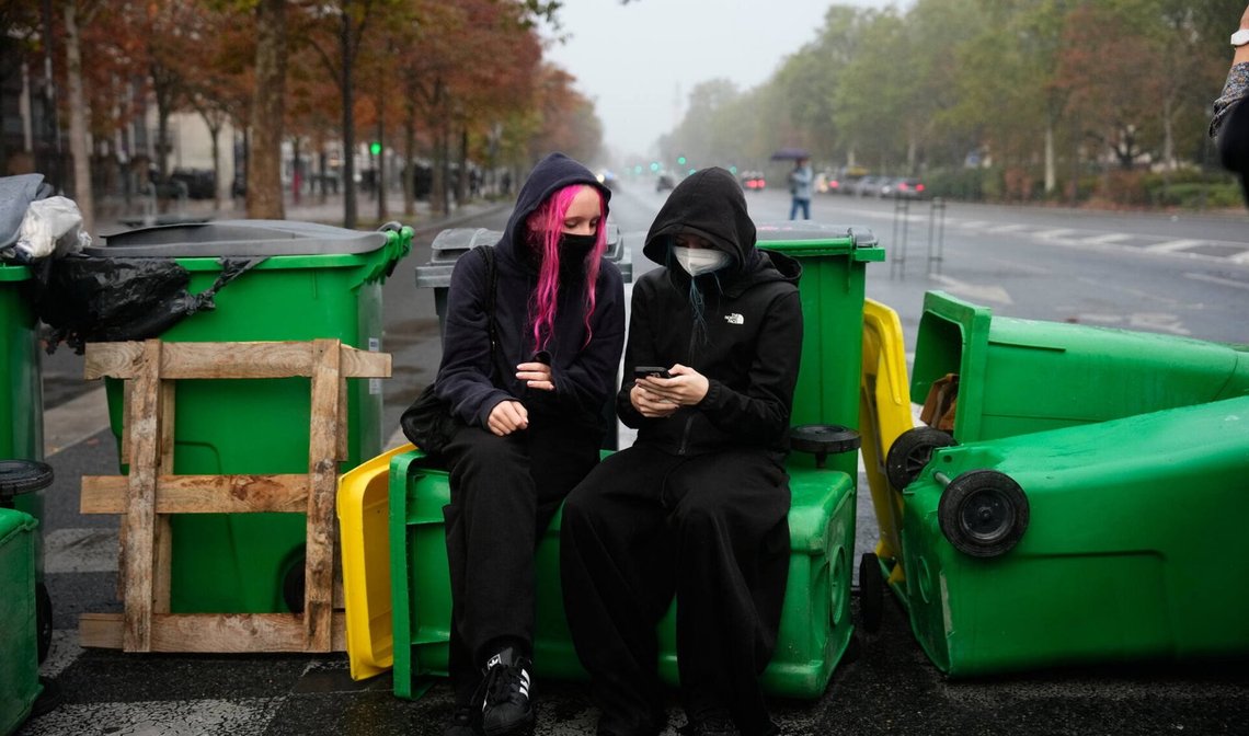 En elev sjekker smarttelefonen sin foran Helene Boucher-gymnaset, som er blokkert med søppelkasser under en demonstrasjon i Paris den 13. oktober 2026. Foto: Teresa Suarez / AP / NTB. En elev sjekker smarttelefonen sin foran Helene Boucher-gymnaset, som er blokkert med søppelkasser under en demonstrasjon i Paris den 13. oktober 2026. Foto: Teresa Suarez / AP / NTB.