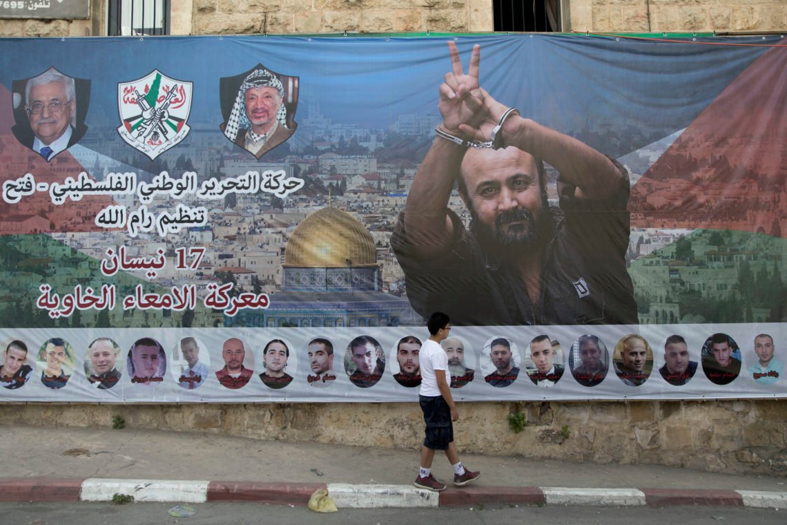 En banderoll med en bild av den fängslade palestinska upprorsledaren Marwan Barghouti och några medfångar. Den arabiska texten lyder: "Palestinian National Liberation Movement, Ramallah organisation, Fatah, 17 april, slaget om de tomma tarmarna". Ramallah på Västbanken. Foto: Nasser Nasser / AP Photo En banderoll med en bild av den fängslade palestinska upprorsledaren Marwan Barghouti och några medfångar. Den arabiska texten lyder: "Palestinian National Liberation Movement, Ramallah organisation, Fatah, 17 april, slaget om de tomma tarmarna". Ramallah på Västbanken. Foto: Nasser Nasser / AP Photo