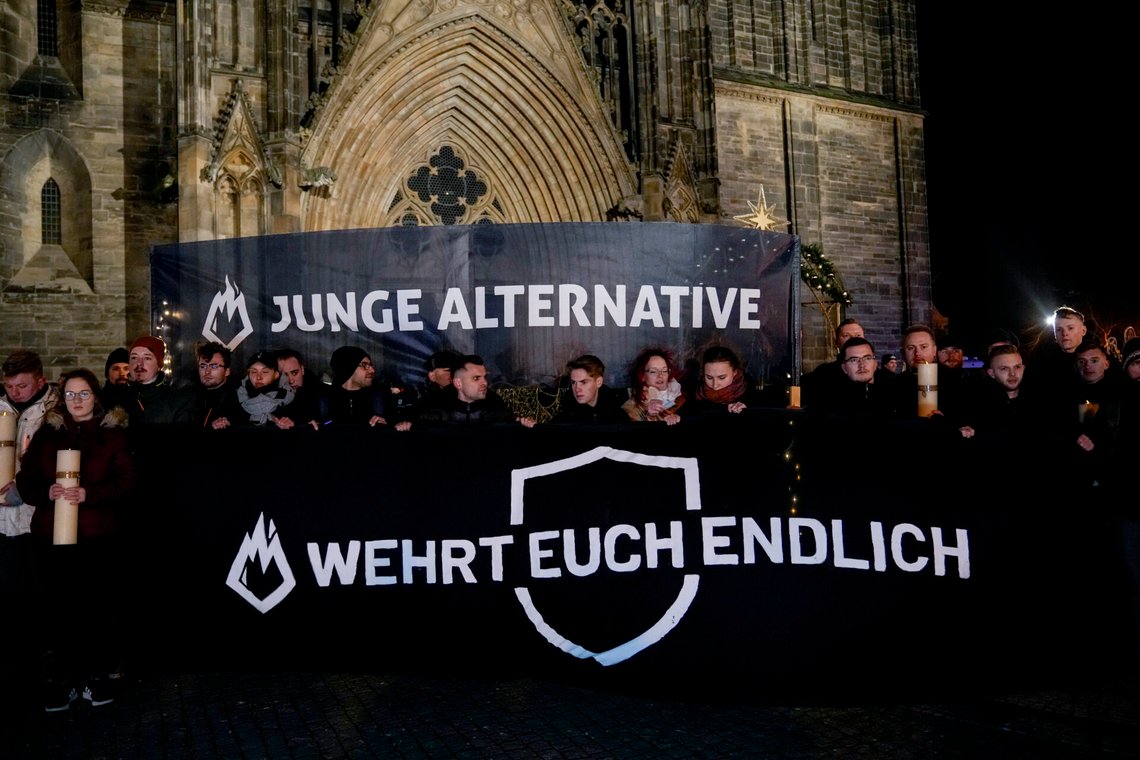 People carry banners reading "young alternative, defend yourself" attending an AfD election campaign in front of the cathedral in Magdeburg, Germany, Monday, Dec. 23, 2024. (AP Photo/Ebrahim Noroozi) People carry banners reading "young alternative, defend yourself" attending an AfD election campaign in front of the cathedral in Magdeburg, Germany, Monday, Dec. 23, 2024. (AP Photo/Ebrahim Noroozi)