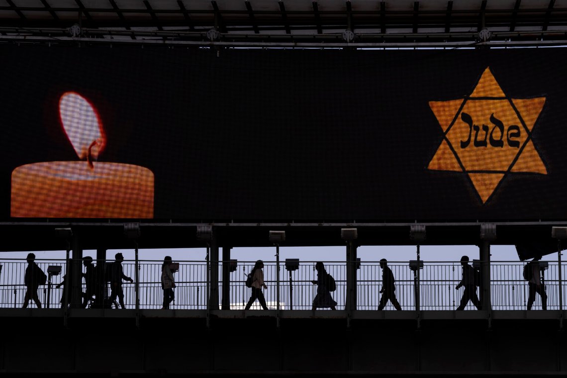 Människor går längs en bro upplyst med en skylt som visar en gul Davidsstjärna med texten "Jude", lik den judar tvingades bära i Nazityskland under den årliga minnesdagen för Förintelsen i Ramat Gan, Israel, 28 april 2022. Foto: Oded Balilty/AP Photo Människor går längs en bro upplyst med en skylt som visar en gul Davidsstjärna med texten "Jude", lik den judar tvingades bära i Nazityskland under den årliga minnesdagen för Förintelsen i Ramat Gan, Israel, 28 april 2022. Foto: Oded Balilty/AP Photo
