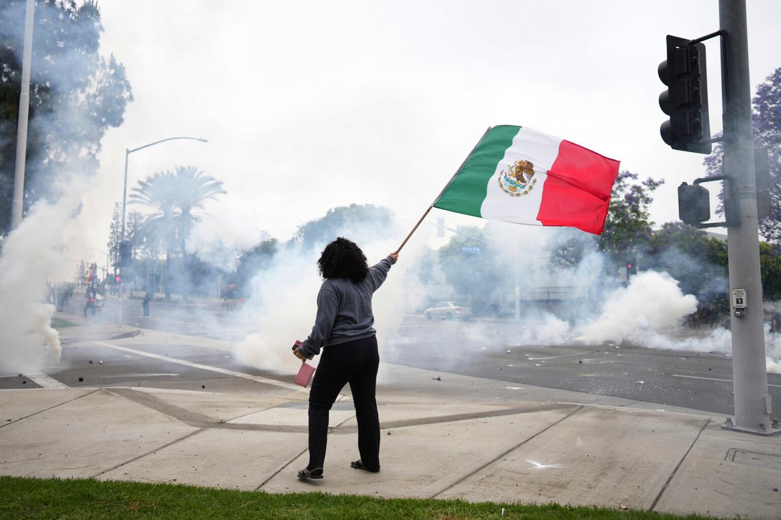 En kvinna viftar med en mexikansk flagga mitt under tårgas från polisen under en protest i Paramount, Kalifornien, den 7 juni 2025, efter att federala immigrationsmyndigheter genomfört operationer. Foto: Eric Thayer/AP Photo En kvinna viftar med en mexikansk flagga mitt under tårgas från polisen under en protest i Paramount, Kalifornien, den 7 juni 2025, efter att federala immigrationsmyndigheter genomfört operationer. Foto: Eric Thayer/AP Photo