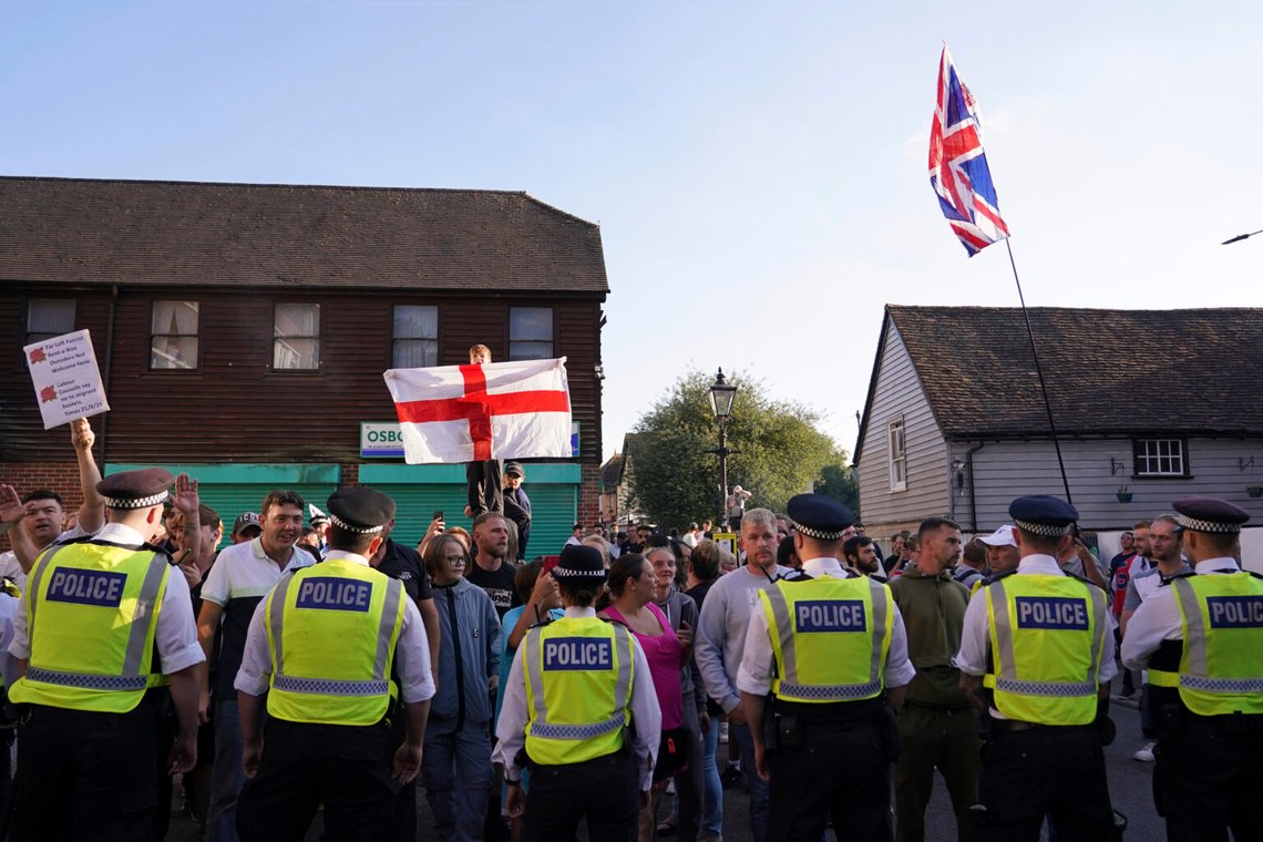 Demonstranter håller flaggor under en demonstration i Orpington nära London, fredagen den 22 augusti 2025, då dilemmat om hur asylsökande ska hysa i Storbritannien blev mer utmanande för regeringen efter att ett betydelsefullt domstolsbeslut denna vecka motiverade motståndare att motarbeta hotell som används som boende. Foto: Alberto Pezzali/AP Photo Demonstranter håller flaggor under en demonstration i Orpington nära London, fredagen den 22 augusti 2025, då dilemmat om hur asylsökande ska hysa i Storbritannien blev mer utmanande för regeringen efter att ett betydelsefullt domstolsbeslut denna vecka motiverade motståndare att motarbeta hotell som används som boende. Foto: Alberto Pezzali/AP Photo