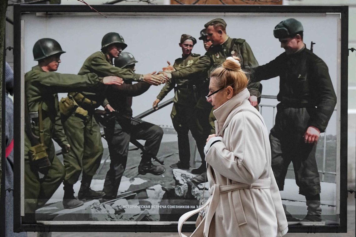En kvinna går förbi en bild av amerikanska, vänster- och sovjetiska trupper som möts den 25 april 1945 vid floden Elbe i Tyskland under andra världskriget på en gatuutställning med färglagda foton tillägnad det senaste firandet av slutet av andra världskriget, i Sankt Petersburg, Ryssland, fredagen den 21 november 2025. Foto: Dmitri Lovetsky/AP Photo En kvinna går förbi en bild av amerikanska, vänster- och sovjetiska trupper som möts den 25 april 1945 vid floden Elbe i Tyskland under andra världskriget på en gatuutställning med färglagda foton tillägnad det senaste firandet av slutet av andra världskriget, i Sankt Petersburg, Ryssland, fredagen den 21 november 2025. Foto: Dmitri Lovetsky/AP Photo