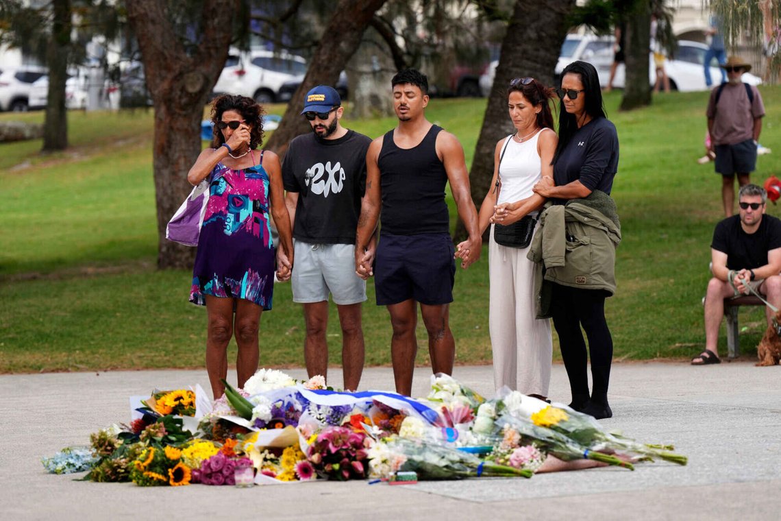 Människor ber över blommor som lagts till minne av de döda vid Bondi Pavilion i Sydney den 15 december 2025. Foto: Mark Baker / AP / NTB. Människor ber över blommor som lagts till minne av de döda vid Bondi Pavilion i Sydney den 15 december 2025. Foto: Mark Baker / AP / NTB.