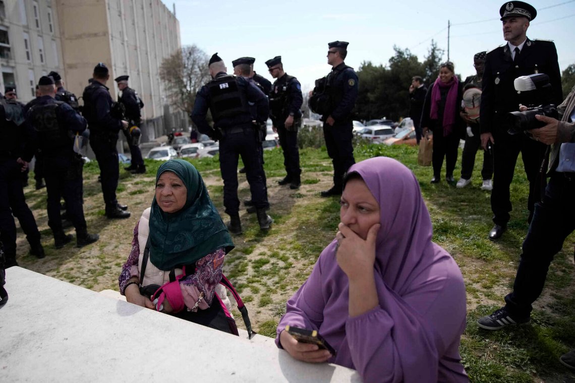 Invånare sitter bredvid franska poliser under Frankrikes president Emmanuel Macrons besök med fokus på säkerhet och bekämpning av narkotikahandel, den 19 mars 2024, i stadsdelen La Castellane i Marseille, södra Frankrike. Foto: Christophe Ena/AP-NTB. Invånare sitter bredvid franska poliser under Frankrikes president Emmanuel Macrons besök med fokus på säkerhet och bekämpning av narkotikahandel, den 19 mars 2024, i stadsdelen La Castellane i Marseille, södra Frankrike. Foto: Christophe Ena/AP-NTB.